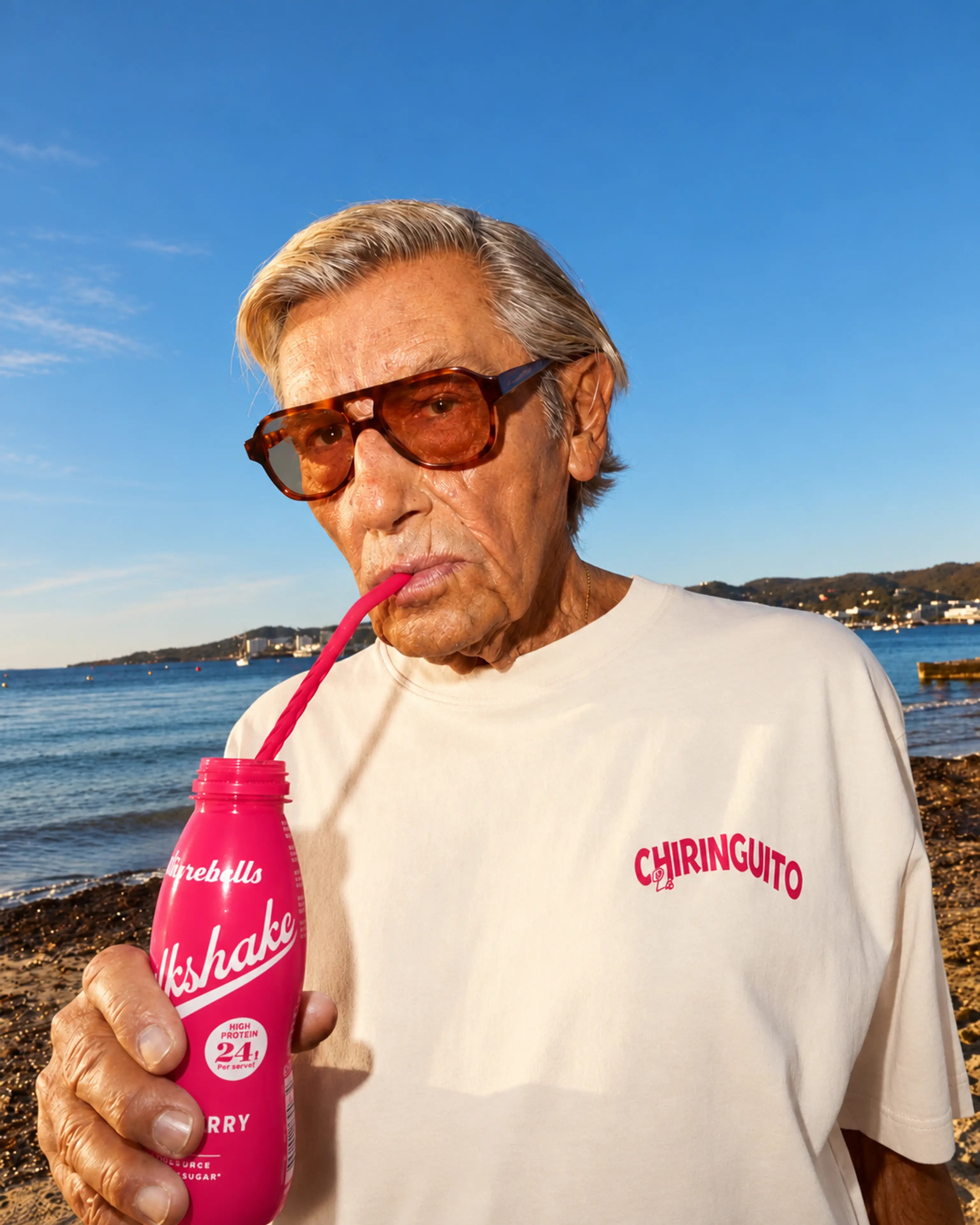 A man in sunglasses enjoying a pink drink by the sea