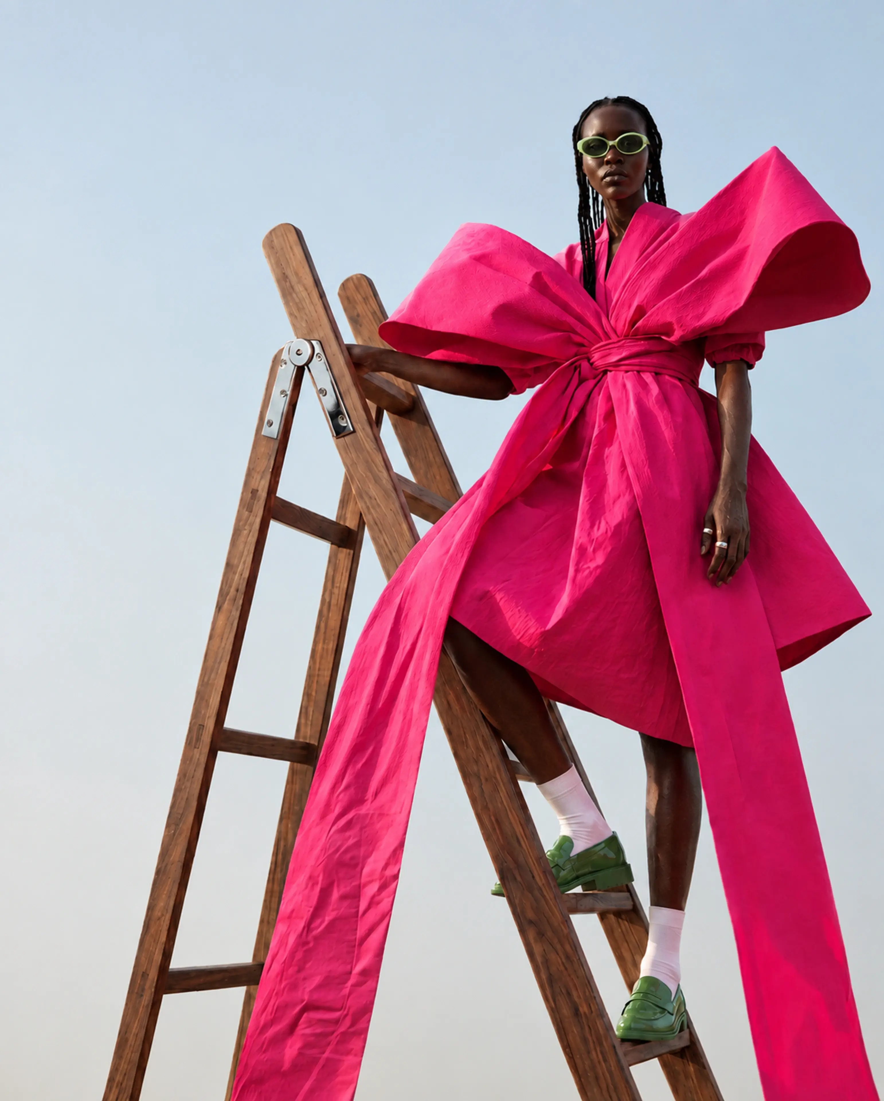 A fashion portrait with an oversized pink bow and a wooden ladder