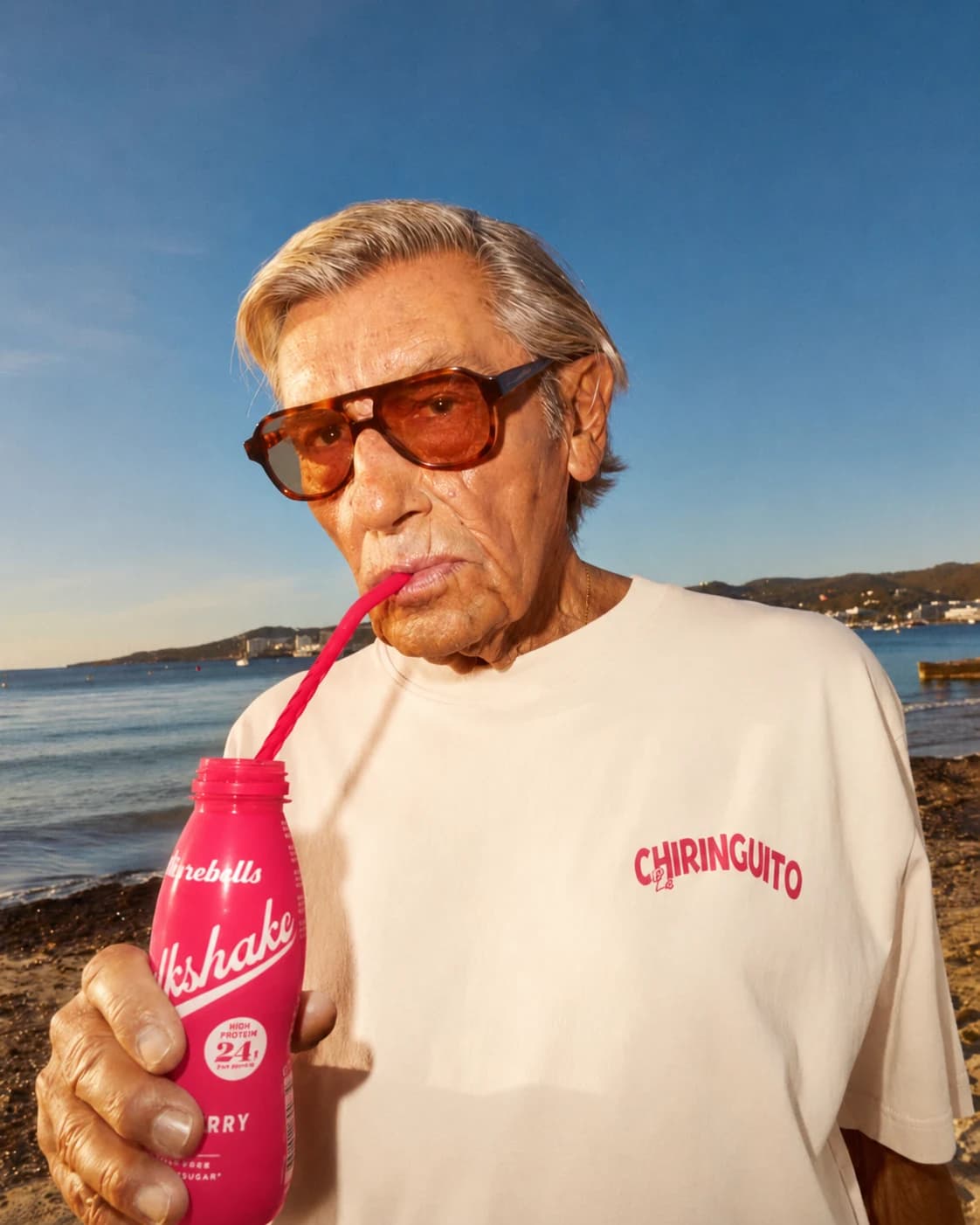 A man in sunglasses enjoying a pink drink by the sea