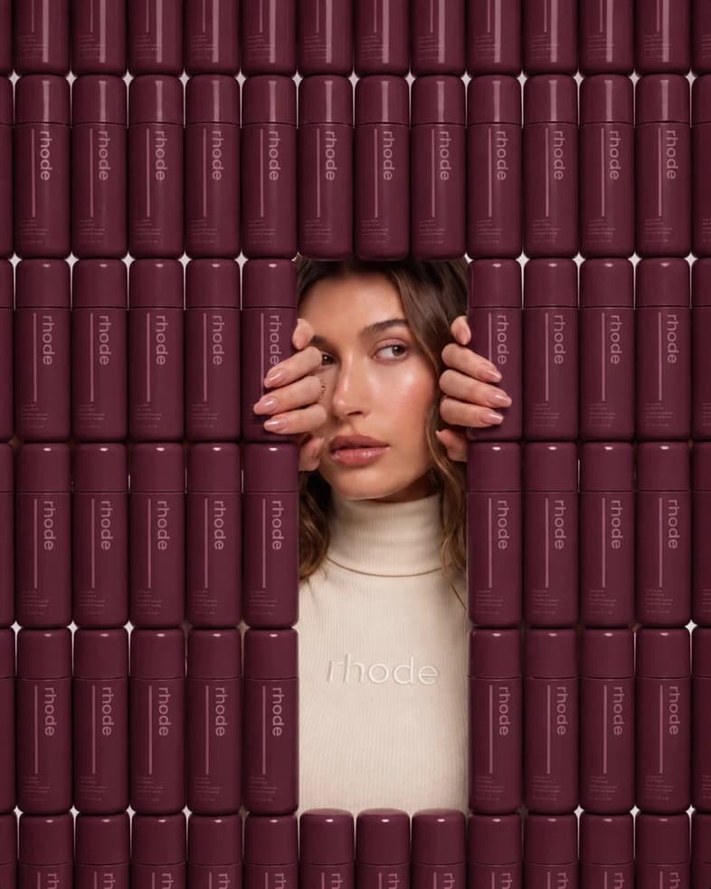 A portrait framed by a wall of deep plum cylindrical objects