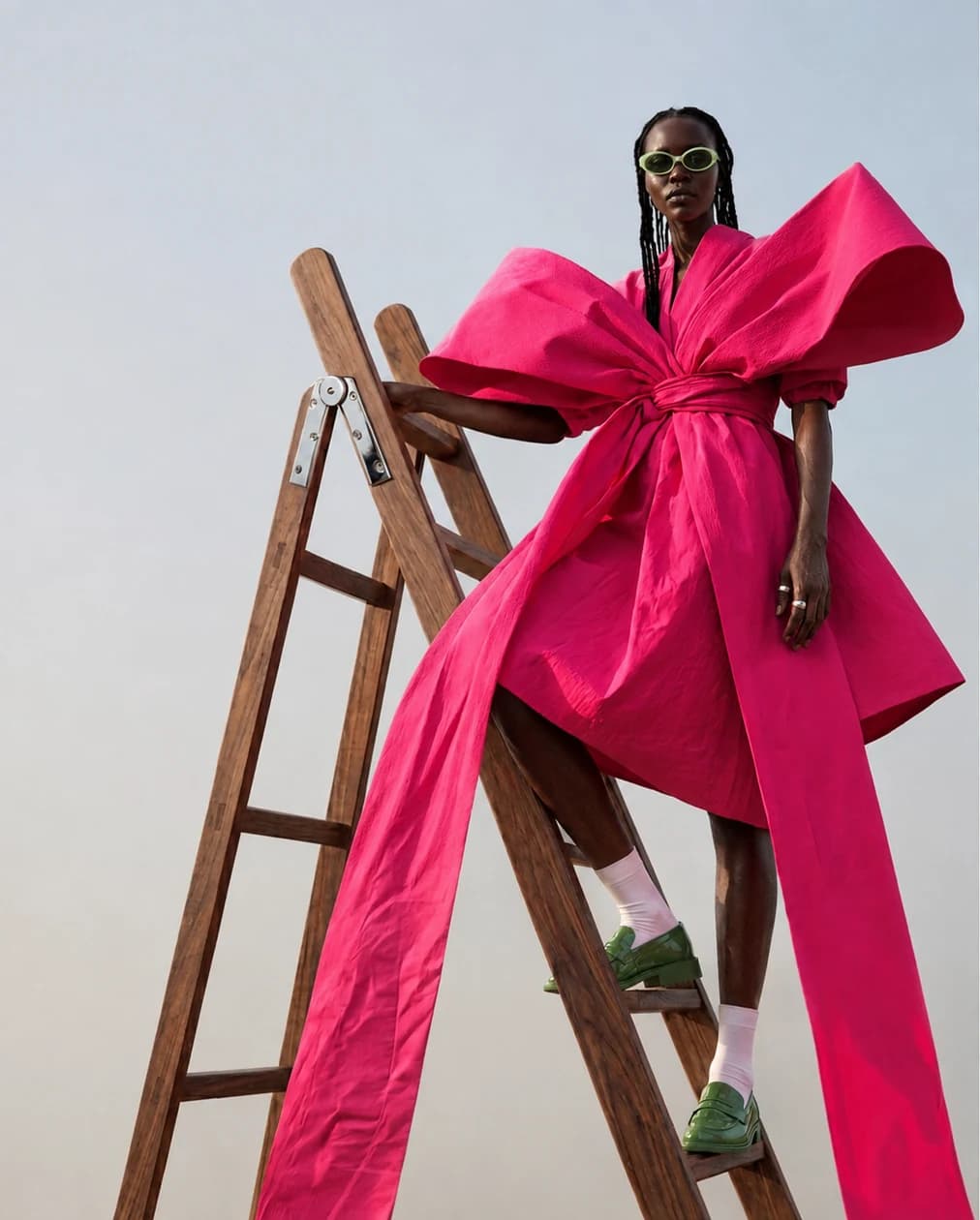 A fashion portrait with an oversized pink bow and a wooden ladder